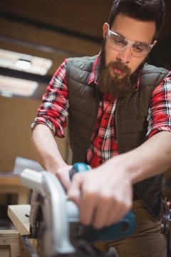 Carpenter using a jigsaw in workshop