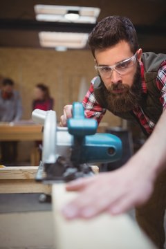 Carpenter using a jigsaw in workshop
