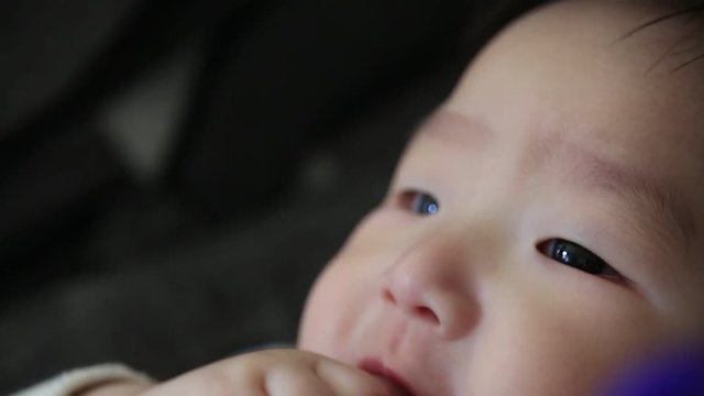 Close up of asian baby boy sucking his fingers and drooling 