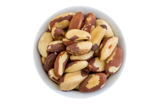 top view of brazil nuts in a ceramic bowl. white background