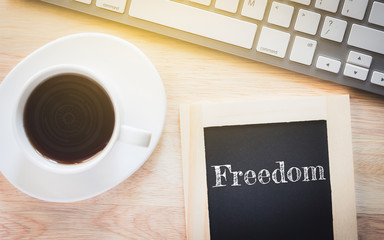 Concept Freedom message on wood boards. A keyboard and a glass coffee table.Vintage tone.
