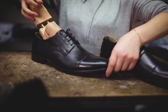 Cobbler placing shoe tree inside the shoes