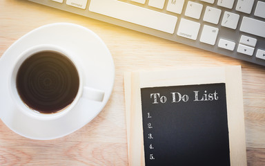 Concept To Do List message on wood boards. A keyboard and a glass coffee table.Vintage tone.