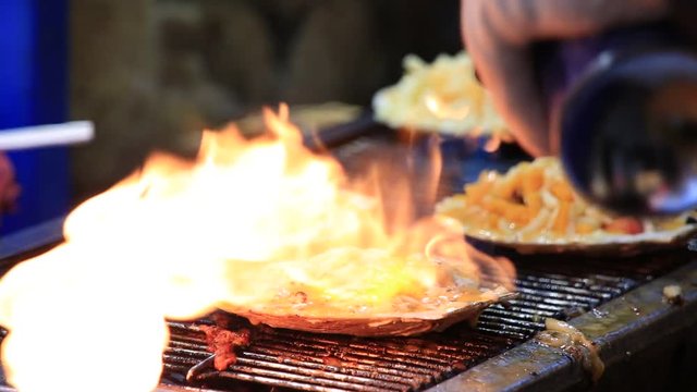 Man making famous grilled scallops at Myeongdong street in Seoul, South Korea 