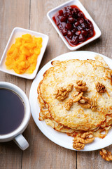 Pancakes, jam, walnuts and coffee on a wooden table