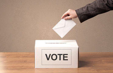 Close up of male hand putting vote into a ballot box