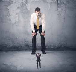 Big business bully looking at small coworker