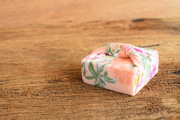 Gift box wrapped with Thai traditional style cloth tie on wood background