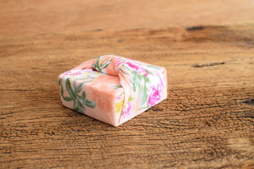 Gift box wrapped with Thai traditional style cloth tie on wood background