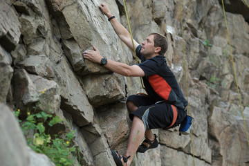 Male rock climber clings to a cliff