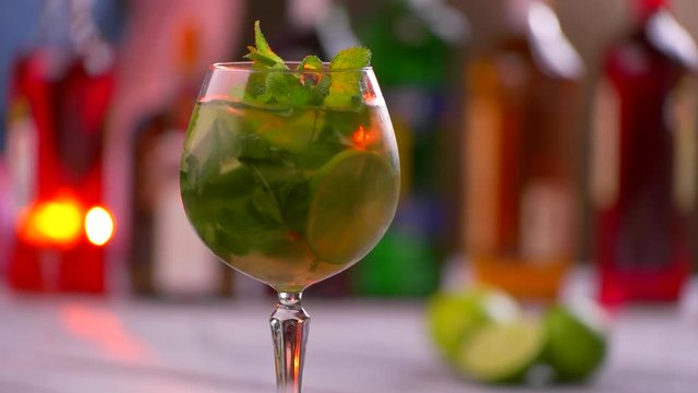 Rotating glass with drink. Beverage with lime and mint. Cocktail served at nightclub. Fresh and cool hugo cocktail.