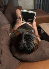 Woman playing with a tactile tablet while laying on a couch in a living room
