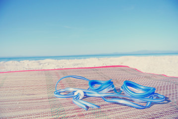 Blue swimming goggles on white beach, with turquoise sea in the background. Filtered image in faded, retro, Instagram style. Nostalgic concept of exotic summer travel and holidays. - 113130005