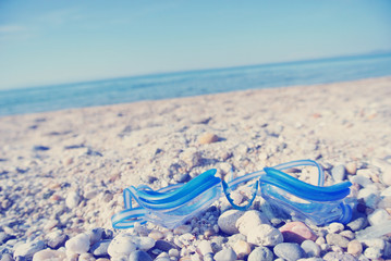 Blue swimming goggles on white beach, with sea in the background; tilted view. Filtered image in faded, retro, Instagram style. Nostalgic concept of exotic summer travel and holidays. - 113130098