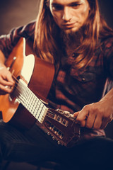Young guitarist is tuning guitar.