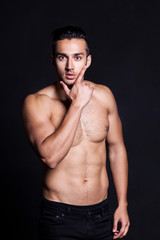 Fototapeta na wymiar Sexy shirtless male model flirting against black background