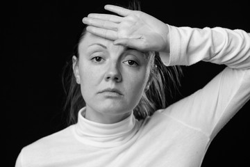 Headache. Close up portrait of a sad woman, holding the hand on the forehead, looking down, isolated on white background, black and white