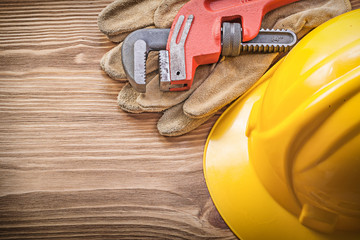 Hard hat safety gloves pipe wrench on wooden board construction 