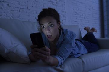 young beautiful woman lying on home couch using mobile phone internet addiction concept