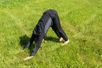 Fototapeta na wymiar Male performs asanas on the grass.