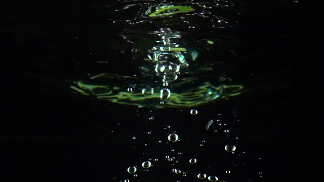 Two lime slices fall under water super slow motion shot. Black background