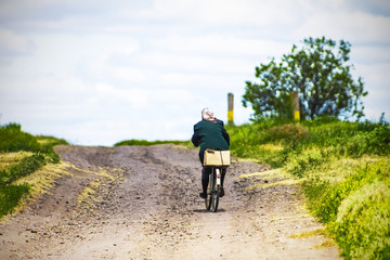 Obraz premium woman riding a bike on a country road, sky background