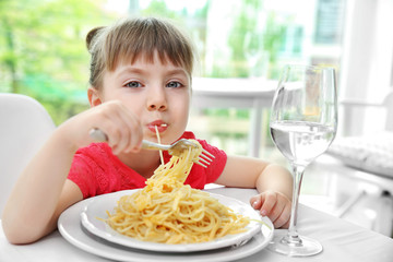 Beautiful small girl eating pasta