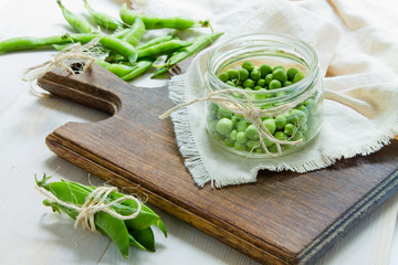Green peas in a bank and pea pods on burlap