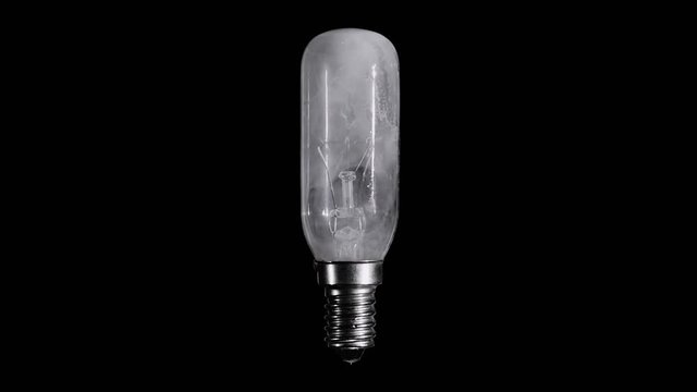 Light bulb lamp flickers and burns out with flame over black background