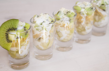 fruit, kiwi, orange and pear in small cups on a light background