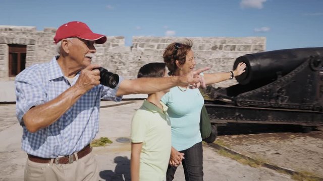 Happy tourists on holidays, during vacation journey. Hispanic people traveling in Havana, Cuba. Grandpa, grandma and grandson having fun. Family trip, senior man with camera, woman, boy. Steadicam