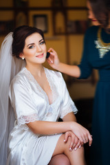 Obraz na płótnie Canvas Beautiful bride wedding with makeup and curly hairstyle. Stylist makes make-up bride on wedding day. Beauty portrait of young woman at morning.