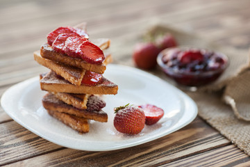Toasts with cutted and fresh strawberry with sour cream and berry jam on wooden backcround