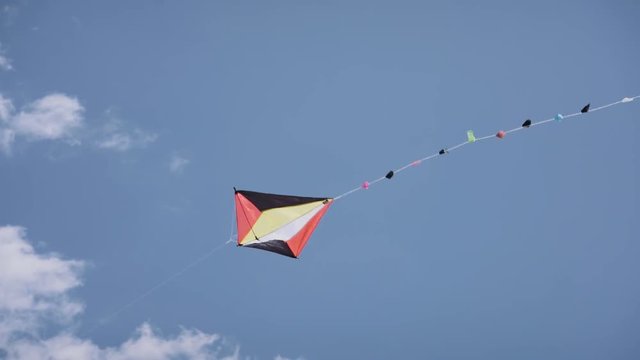 Colorful kite flying in sunny summer clear sky. Toy for child fun, leisure activities, recreation. Slow motion, slow-motion, slowmo, slowmotion. Copy space