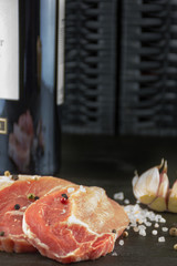Raw pork steaks with salt, pepper, garlic and a bottle of red wi