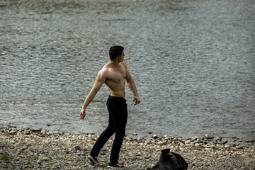 muscular man with bag near water