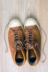 Old leather sneakers on wooden background top view, tonned verti
