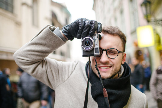 Young hipster taking pictures outdoor using old film camera