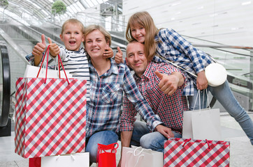 Family with shopping bags in the shopping center showing thumbs