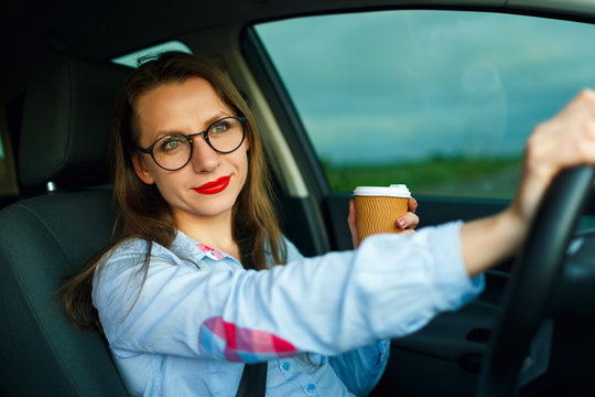 Young Woman With Coffee To Go Driving Her Car