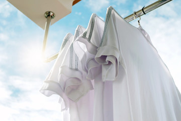 Fototapeta na wymiar White T-shirts on clothesline against blue sky.