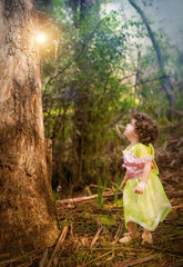 little girl dressed as a fairy standing in forest