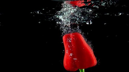 Red bell pepper falls into water super slow motion, black background - Powered by Adobe