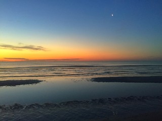 la luna si specchia all'alba sul mare