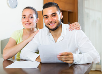 Happy couple with documents indoors.