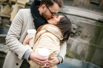 Young hipster couple  with coffee kissing, hugging in old town