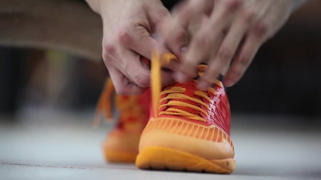 The athlete tying shoelaces on sneakers. Preparation for the exercise. Close-up.