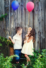 Boy and Girl with pink and blue Balloons in the Garden. Love Romantic Concept. Rustic Background