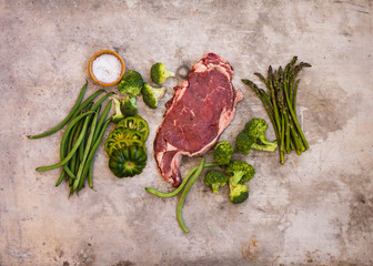 Overhead of beef steak, fresh green vegetable ready to prepare dinner grill meal.