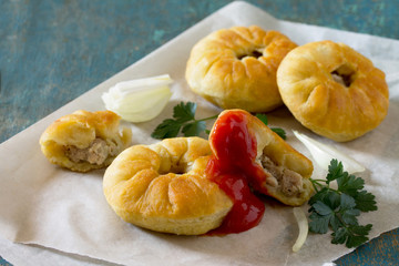 Open pies with meat (belyashi) on vintage wooden table.